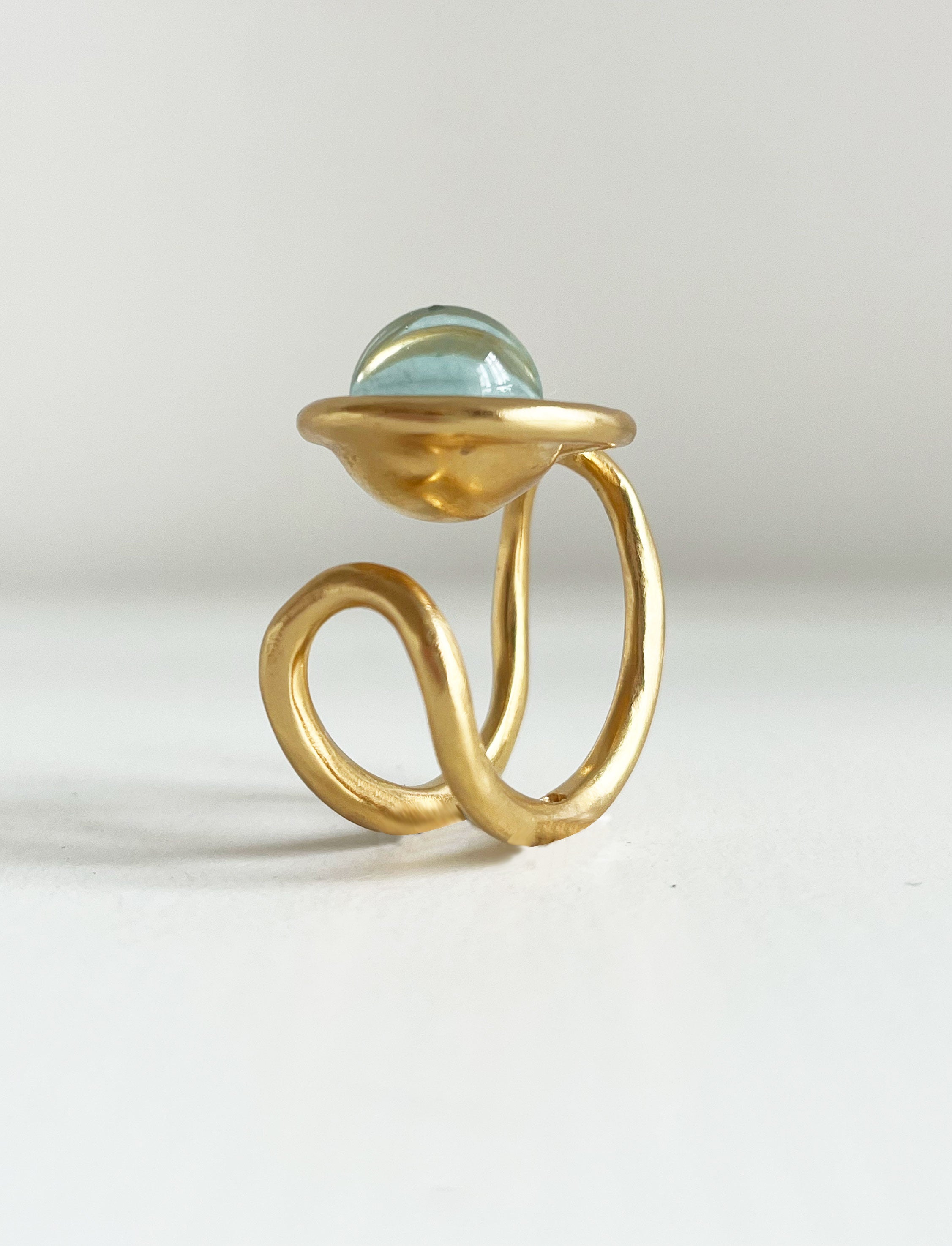 une chevalière eclipse en vermeil, vue de profil, trois quart. on voit la forme du corps de bague, sur le dessus la perle de verre de murano ronde entourée de la première boucle du huit. 
