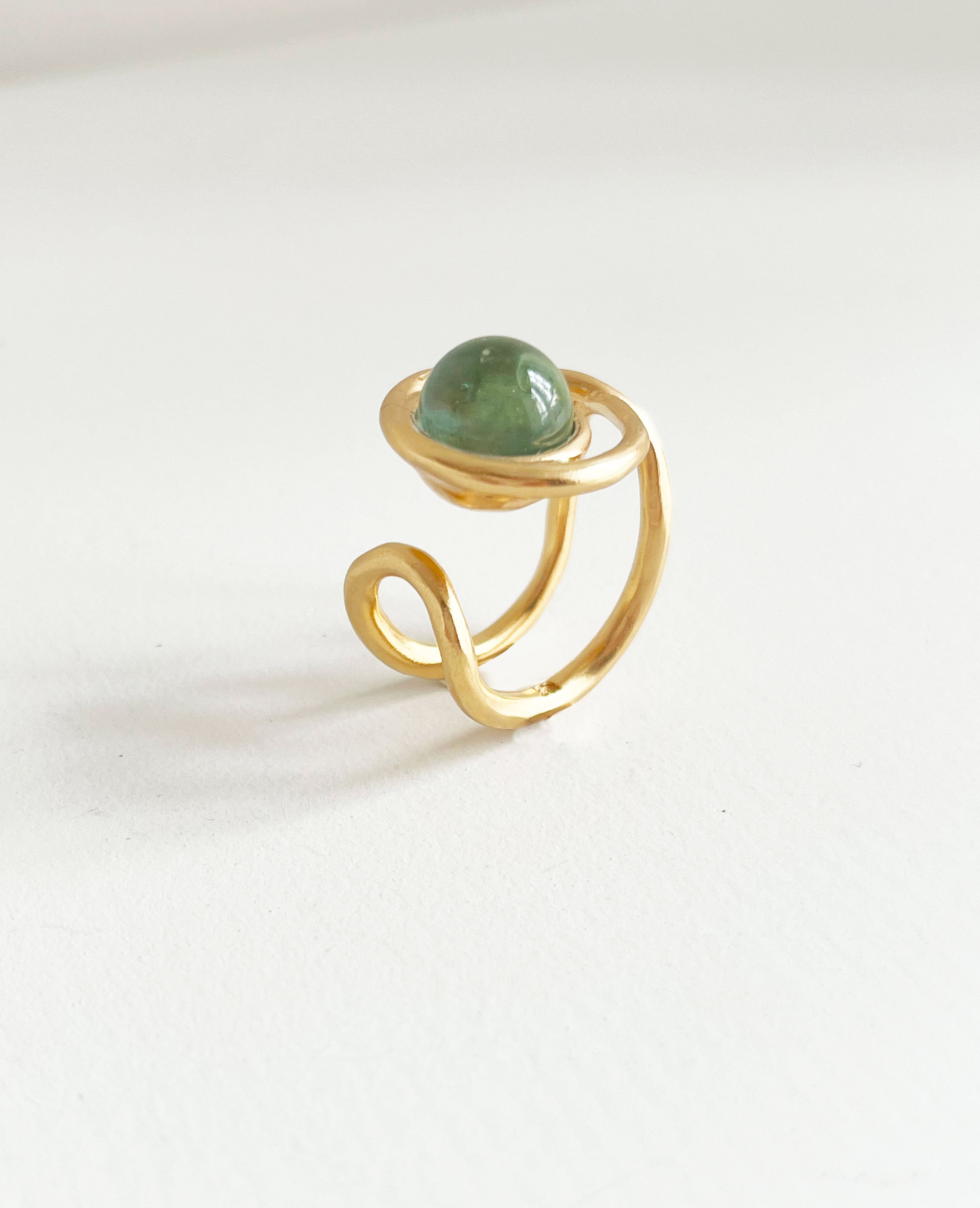une chevalière eclipse en vermeil, vue de profil, trois quart. on voit la forme du corps de bague, sur le dessus la perle de verre de murano ronde entourée de la première boucle du huit. vue legerement de dessus
