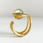 une chevalière eclipse en vermeil, vue de profil. on voit la forme du corps de bague, sur le dessus la perle de verre de murano ronde entourée de la première boucle du huit