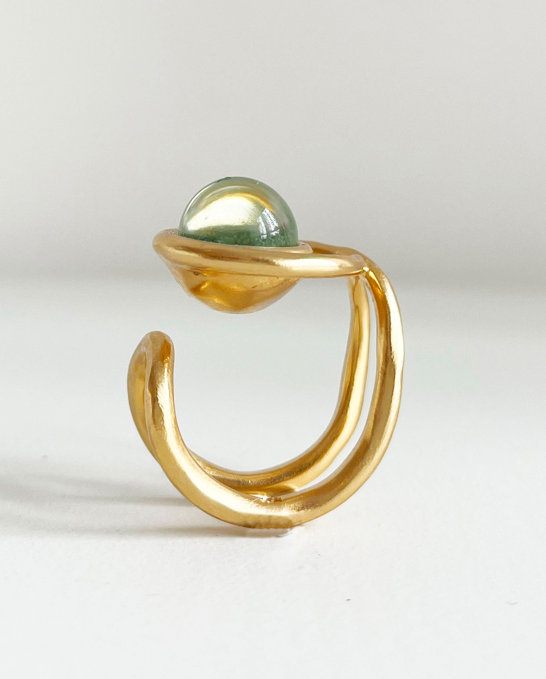 une chevalière eclipse en vermeil, vue de profil. on voit la forme du corps de bague, sur le dessus la perle de verre de murano ronde entourée de la première boucle du huit